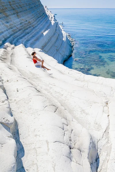 Uma menina senta-se em uma encosta de penhasco branco chamado "Scala dei Turchi " — Fotografia de Stock