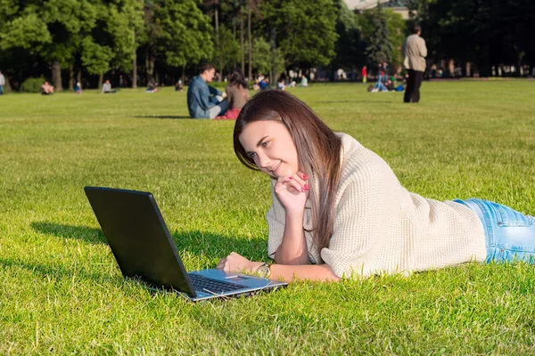 Jeune femme sur une herbe dans le parc ou le jardin en utilisant un ordinateur portable — Photo