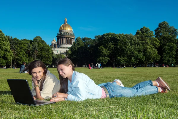 Bir dizüstü bilgisayar ile parkta iki kız — Stok fotoğraf