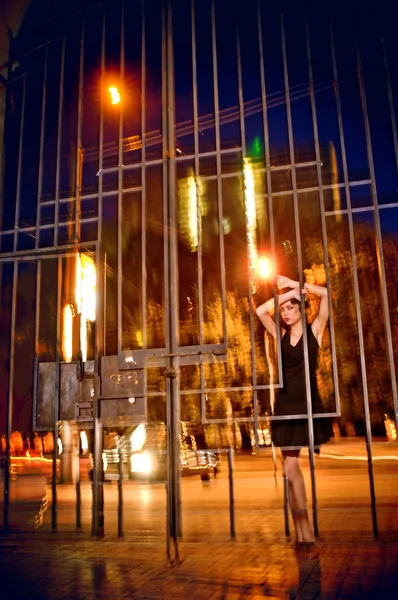 Pretty woman posing in cage outdoors at night — Zdjęcie stockowe