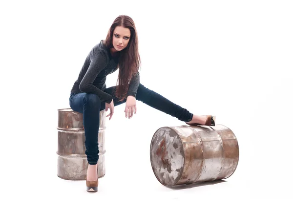 Girl in jeans sitting on the iron barrel — Stock Photo, Image