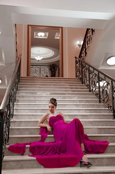 Mujer en un vestido largo está sentado en las escaleras — Foto de Stock