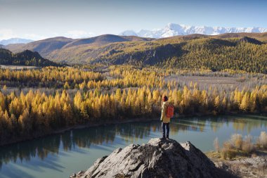 Altai Dağları 'ndaki nehir vadisine bakan sırt çantalı adam.