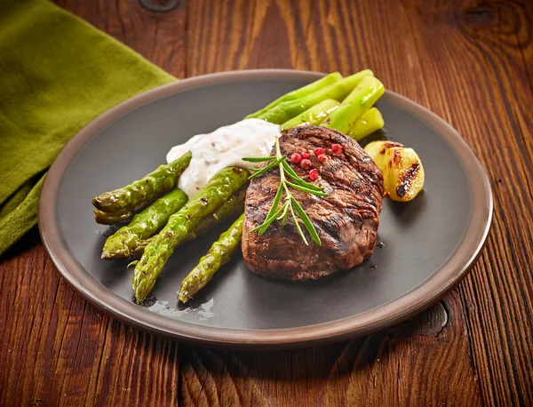 Steak de bœuf grillé et asperges sur assiette foncée — Photo