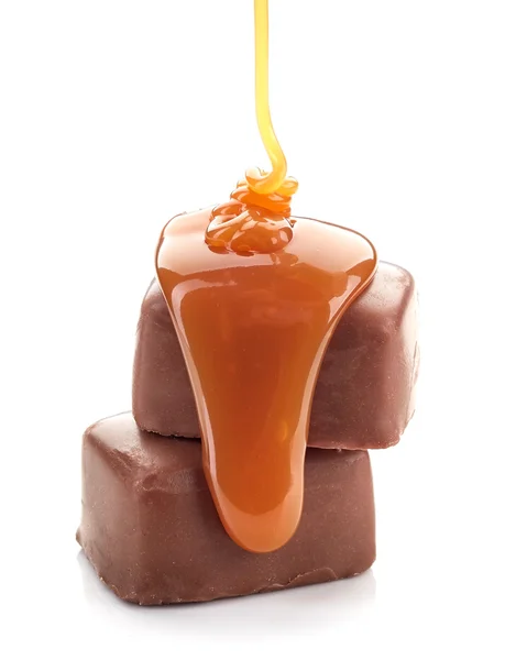 Caramel sauce flowing on chocolate candies — Stock Photo, Image