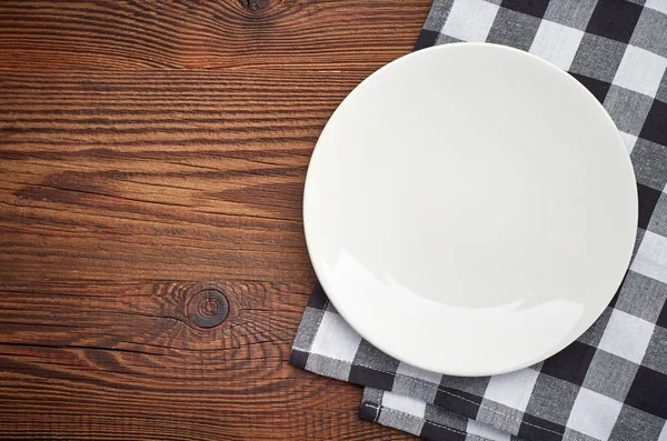Napkin and white plate on wooden table — Stock Photo, Image