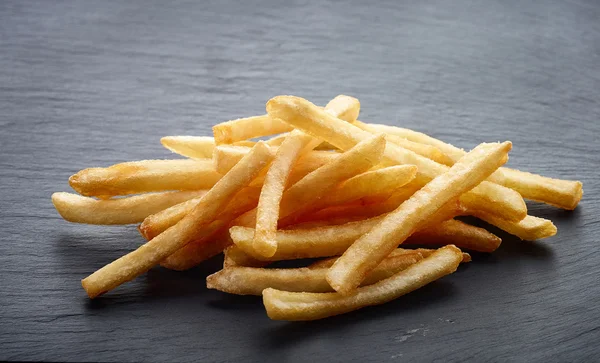 Batatas fritas no fundo de pedra preta — Fotografia de Stock