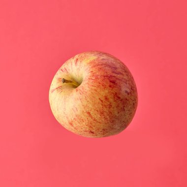 Pembe arka planda izole edilmiş tek bir çiğ elma.