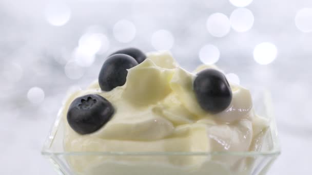 Tomar una cucharada de crema de mascarpone batida y arándanos sobre un fondo festivo bokeh plata — Vídeo de stock