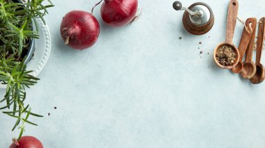 Açık mavi mutfak masasında kırmızı soğan ve baharat kompozisyonu.