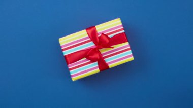 Kırmızı kurdeleli renkli hediye kutusu mavi arkaplan üzerinde hareket ediyor, üst görünüm, dur hareket animasyonu