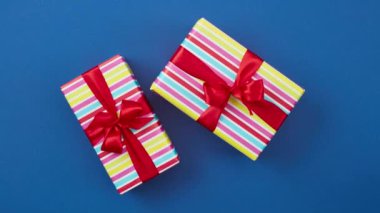 Kırmızı kurdeleli renkli hediye kutuları mavi arkaplan, üst görünüm, dur hareket animasyonu üzerinde hareket