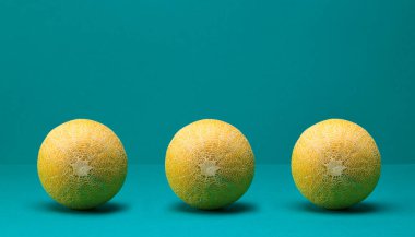 Turkuaz renkli arka planda üç taze olgun kavun.