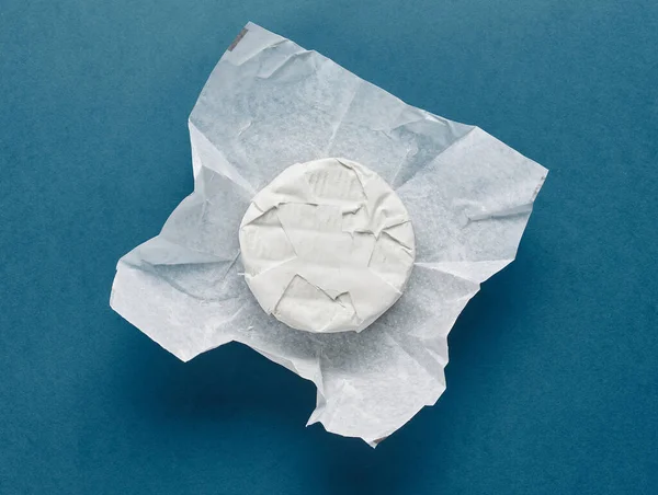 Mavi kağıt arka planda ambalaj kağıdında taze peynir, üst görünüm