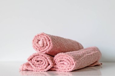 Pastel pembe banyo havlusu rafta yuvarlanıyor, seçici odaklı.