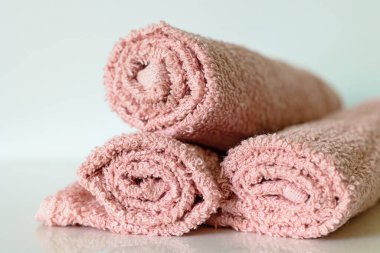 Pastel pembe banyo havlusu rafta yuvarlanıyor, seçici odaklı.