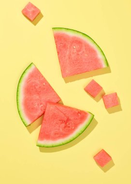 Sarı arka planda izole edilmiş taze karpuz dilimleri ve parçalar.