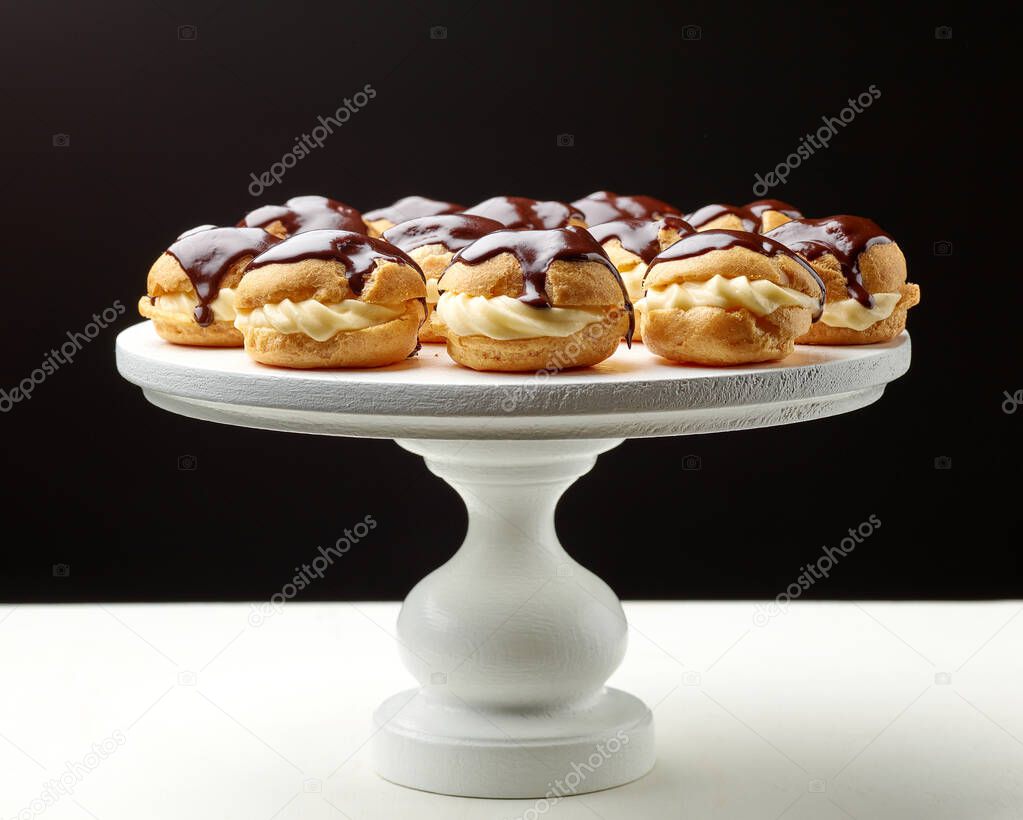 freshly baked cream puffs on white wooden cake stand