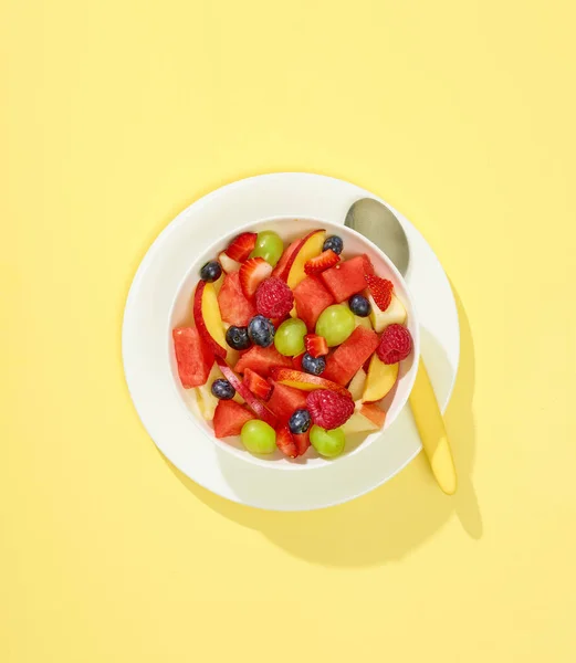 黄色の背景に新鮮なフルーツサラダのボウルトップビュー — ストック写真