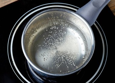 Su ısıtıcısı elektrikli indüksiyon sehpasında ahşap mutfak masasında.