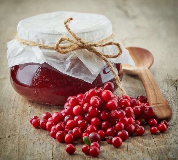 Fresh raw cowberries and jar of jam — Stock Photo, Image