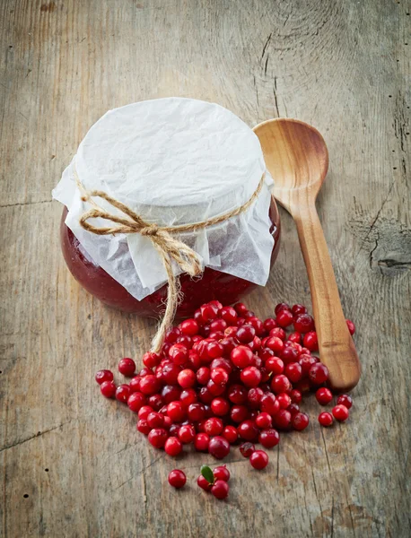 Fresh raw cowberries and jar of jam — Stock Photo, Image
