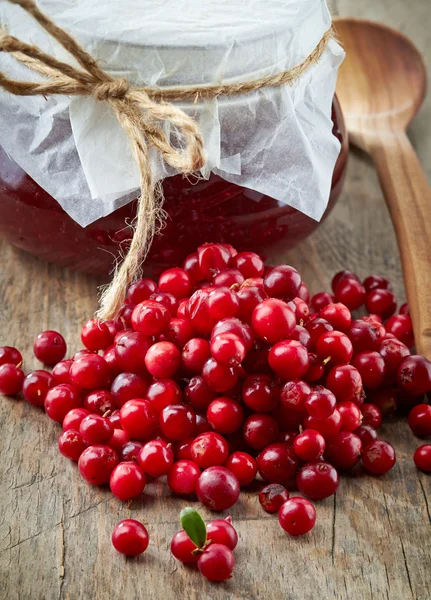 Fresh raw cowberries and jar of jam — Stock Photo, Image