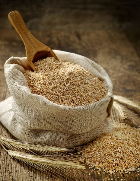 Wheat grits sack on old wooden table — Stock Photo, Image