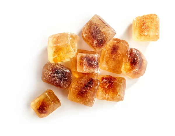 Cubos de azúcar caramelizados marrón sobre un fondo blanco —  Fotos de Stock