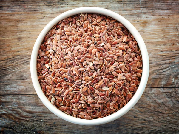 Bowl of flax seeds on old wooden table — Stock Photo, Image