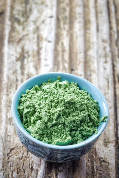 Bowl of wheat sprouts powder on wooden background — Stock Photo, Image