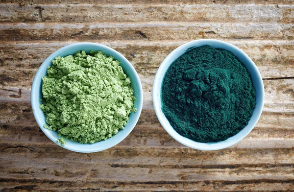 Ciotola di polvere di alghe spirulina e germoglio di grano in polvere su legno — Foto Stock