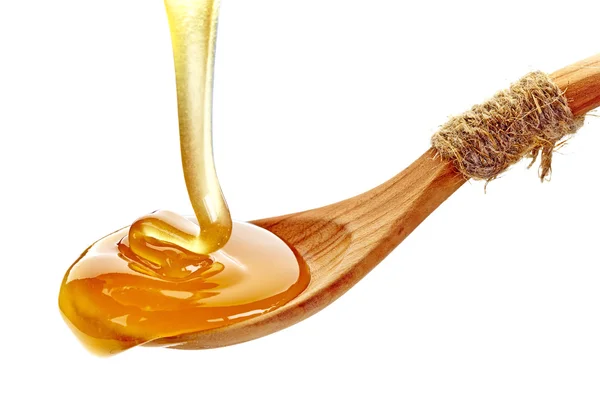 Honey pouring into wooden spoon — Stock Photo, Image