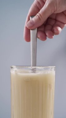 İnsan eli bardaktaki suyla protein tozunu karıştırıyor. beyaz spor beslenmesi. Spor ya da diyet içeceği hazırlamak için kuru karışım.