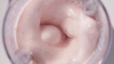 Çilekli ve muzlu, pembe milkshake karışımı. Üst Manzara. Ağır çekim. Sağlıklı protein smoothie içecek konsepti, yiyecek yakın çekim