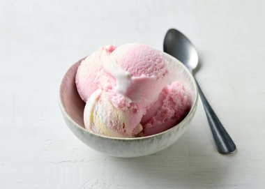 bowl of pink raspberry ice cream on white table background