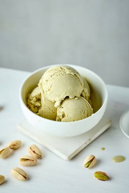 bowl of pistachio ice cream on white table background
