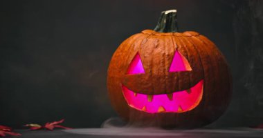 Siyah arka planda parlayan kırmızı gözlü ve dumanlı ürkütücü Cadılar Bayramı Balkabağı