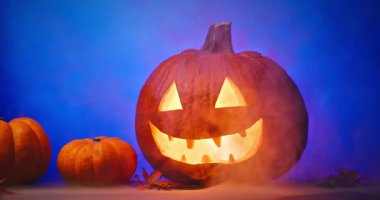 Siyah arka planda parlayan kırmızı gözlü ve dumanlı ürkütücü Cadılar Bayramı Balkabağı