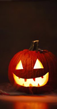 Siyah arka planda parlayan kırmızı gözlü ve dumanlı ürkütücü Cadılar Bayramı Balkabağı