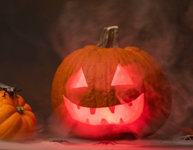 Siyah arka planda parlayan kırmızı gözlü ve dumanlı ürkütücü Cadılar Bayramı Balkabağı