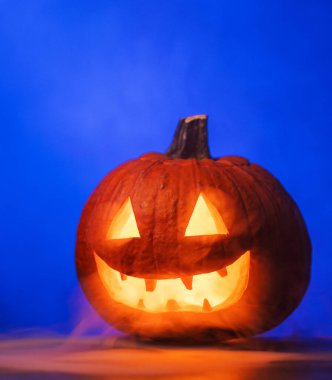 Ürkütücü Cadılar Bayramı Balkabağı Parlayan Kırmızı Gözler ve Mavi Fonda Duman