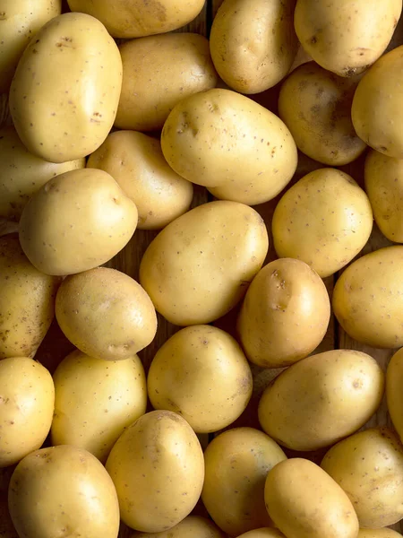 Çiğ sarı patatesler çerçeveyi doğal gıda arka planıyla dolduruyor.