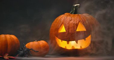 Siyah arka planda parlayan kırmızı gözlü ve dumanlı ürkütücü Cadılar Bayramı Balkabağı