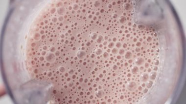 Çilekli ve muzlu, pembe milkshake karışımı. Üst Manzara. Ağır çekim. Sağlıklı protein smoothie içecek konsepti, yiyecek yakın çekim