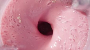 Çilekli ve muzlu, pembe milkshake karışımı. Üst Manzara. Ağır çekim. Sağlıklı protein içeceği konsepti, yiyecek yakın çekimi. Smoothie 'de protein tozu