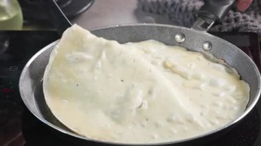 Aşçı kızartma tavasında krep çevirir. Mutfaktaki sıcak tavada taze pişmiş krep yakın plan. Sağlıklı kahvaltı için evde leziz krep yapma süreci, yiyecek kapanıyor.