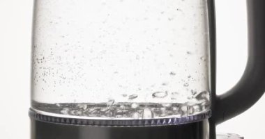 Elektrikli çaydanlıkta kaynar su, yakın plan yiyecek ve içecek, şeffaf cam bir elektrikli su ısıtıcısının içinde kaynayan ve kaynayan suyun yakın plan çekimi. Sıcak buhar ve kabarcıklar