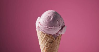 Waffle külahında bir kepçe çilekli dondurma pembe arka planda dönüyor, yiyecek yakın plan