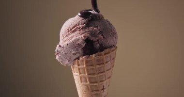 Erimiş çikolata sosu bir top çikolatalı dondurmanın üzerine akıyordu. Kahverengi bir arka planda hazırlanmıştı.